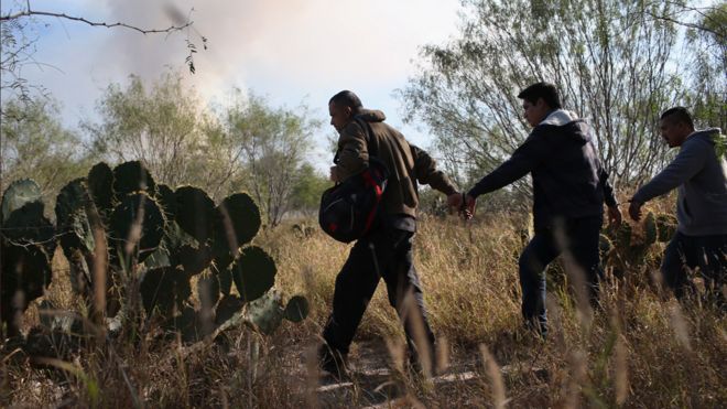 Immigrants walk handcuffed after illegally crossing the US-Mexico border and being caught by the US Border Patrol on December 7, 2015 near Rio Grande City, Texas