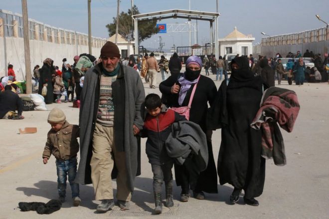 Syrian refugees walk at a Turkish border crossing