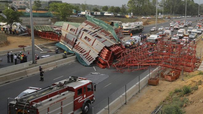 The collapsed bridge lies across the highway, blocking traffic