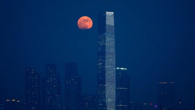 The moon rises over Victoria Harbour in Hong Kong, Monday, Nov. 14, 2016