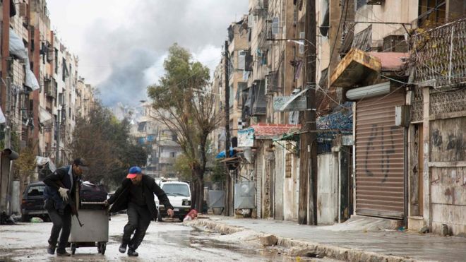 Smoke is seen billowing in the background on December 14, 2016 in this picture taken in a rebel-held neighbourhood in the northern city of Aleppo