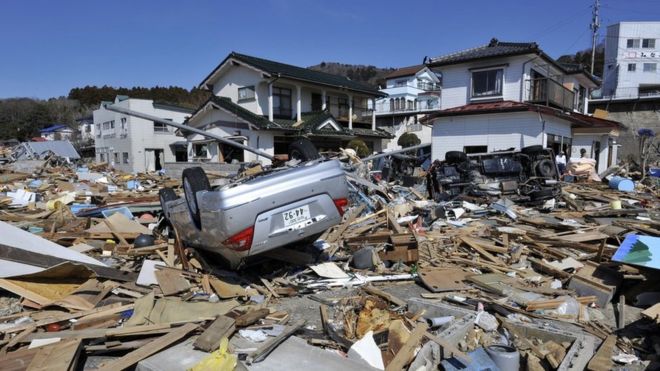Debris, collapsed houses and an upturned car in the aftermath of the 2011 earthquake and tsunami