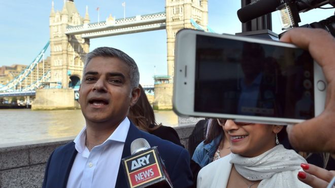 Sadiq Khan is photographed with a mobile phone in front of Tower Bridge, London
