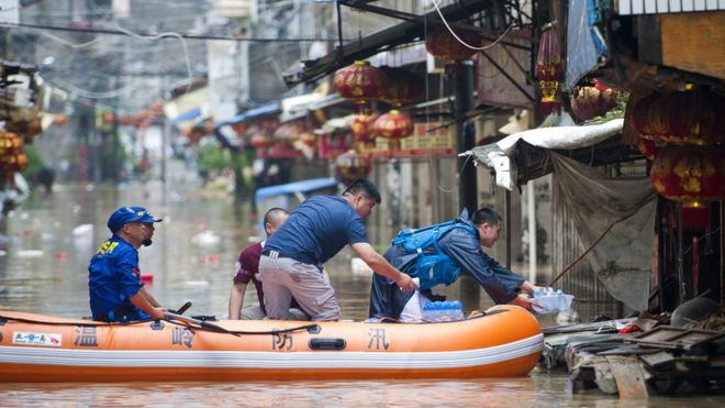 Rescuers distribute drinking water along flooded street in Wenling, eastern China's Zhejiang province on August 10, 2015
