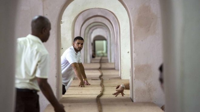 Workers help Cuban cigar roller Jose Castelar, hand roll a 90-meter cigar, stretching through many rooms, in Havana, Cuba, Friday, Aug. 12, 2016