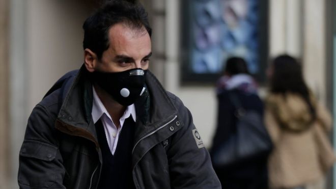 A cyclist wears a protective mask as he pedals in downtown Rome. 24 December 2015.