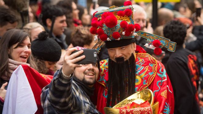 A man takes a selfie with a performer during the Chinese New Year parade in London
