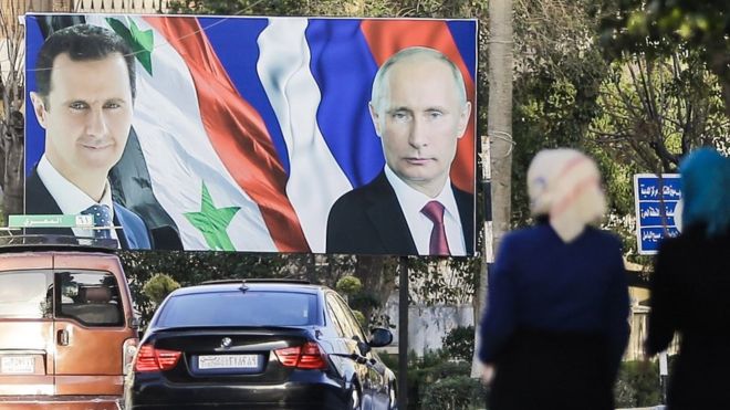 Syrian women walk past a giant poster of President Bashar al-Assad (L) and his Russian counterpart Vladimir Putin (R) in Aleppo (9 March 2017)