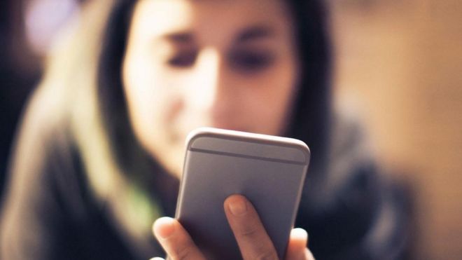 Una joven viendo su teléfono inteligente