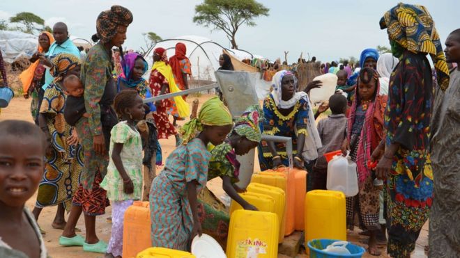 Displaced Nigerians who have fled Boko Haram fill water containers at a camp in Niger