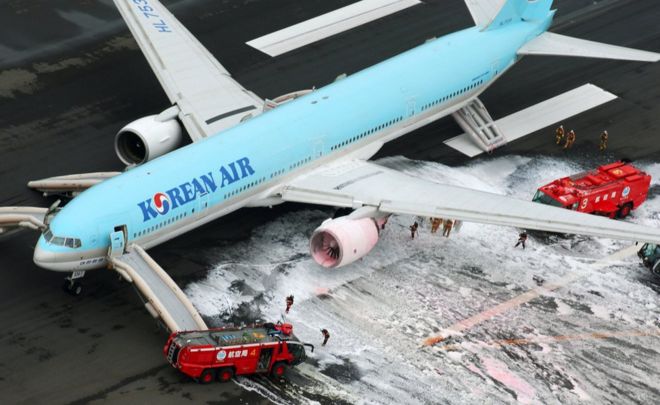 An aerial picture showing a Korean Air with fire trucks spraying foam at an engine, at Haneda airport in Tokyo 27 May 2016