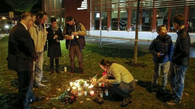 People light candles and lay down flower after a masked man wielding what looked like a sword stabbed four people at a school in Trollhattan, Southern Sweden, 22 October 2015.