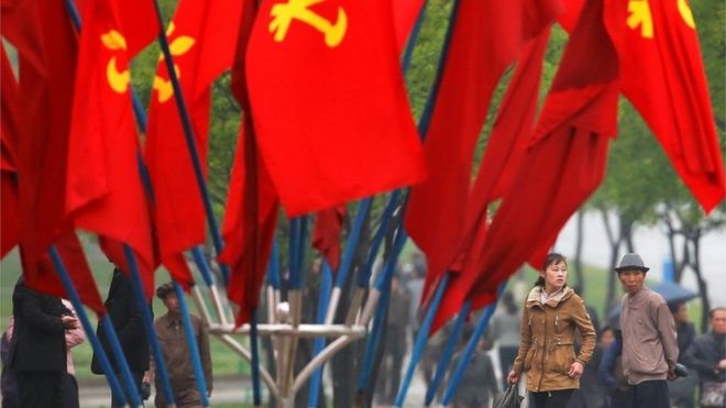 People walk behind party flags placed near April 25 House of Culture, the venue of Workers" Party of Korea (WPK) congress in Pyongyang