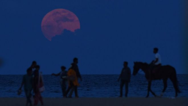 An Indian man rides a horse past people watching the