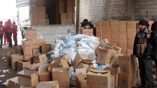Aid parcels and boxes are offloaded from vehicles in a warehouse in Idlib