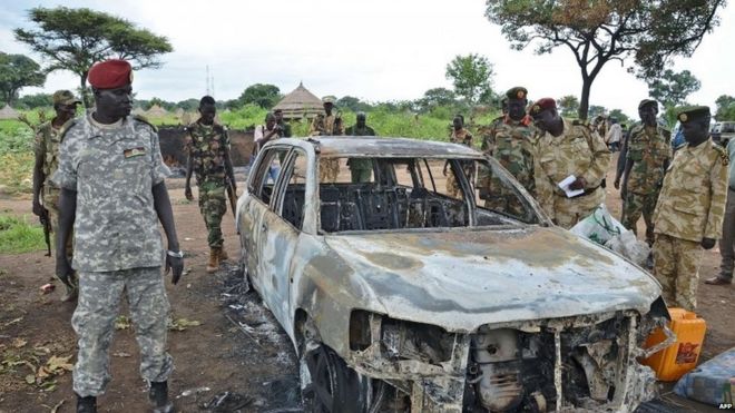 South Sudanese SPLA soldiers inspect a burned out car in Pageri in Eastern Equatoria state on August 20, 2015.