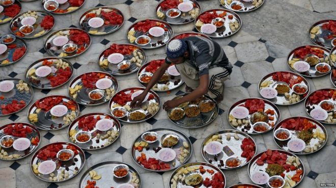 A Muslim man prepares plates of food for an Iftar meal inside a mosque during Ramadan in Ahmedabad, India