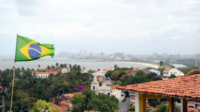 A Brazilian flag flying over a house with the coastal line of Recife seen in background in the north-eastern Brazilian city of Olinda in the state of Pernambuco, September 2010.