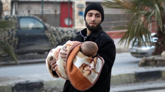 Dinc sakinlərin çoxu üsyançıların ərazilərini tərk etsədə, bu kişi əlindəki uşaqla birgə həmin ərazidə qalmaqdadır (12 dekabr 2016)