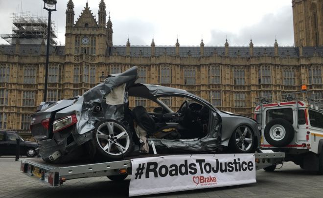 A wrecked car on a trailer outside the Palace of Westminster