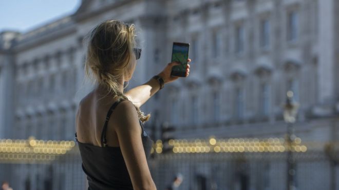 A woman playing Pokémon Go outside Buckingham Palace