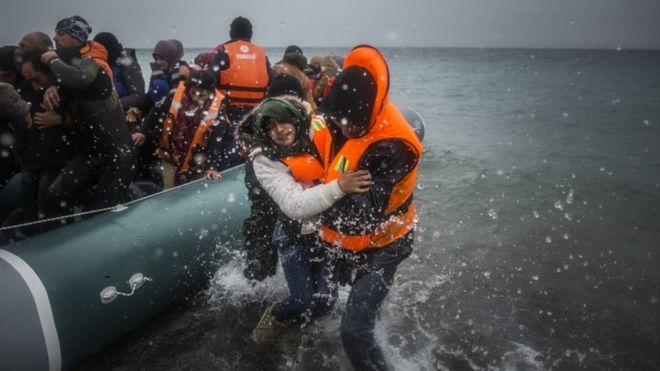 Refugees and migrants disembark on a beach after crossing a part of the Aegean sea from Turkey to the Greek island of Lesbos, on 3 January 2016