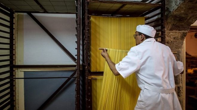 A man dries fresh pasta in a factory