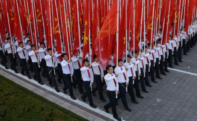 People holding flags during the military parade for the 70th anniversary of the founding Workers' Party, Pyongyang, North Korea - Saturday 10 October 2015