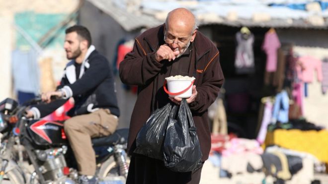 Un hombre come comida que fue distribuida como ayuda en una zona sitiada por los rebeldes en Alepo, Siria (6 de noviembre de 2016).