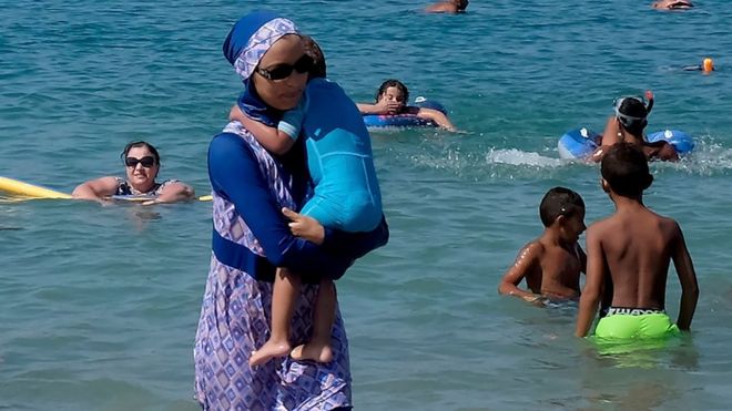 A woman wearing a burkini walks in the water on a beach in Marseille, France. Photo: 27 August 2016