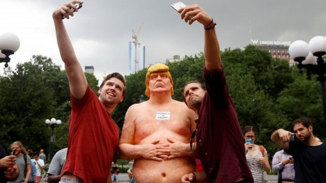 People pose for selfies with a naked statue of Donald Trump in New York's Union Square Park. Photo: 18 August 2016