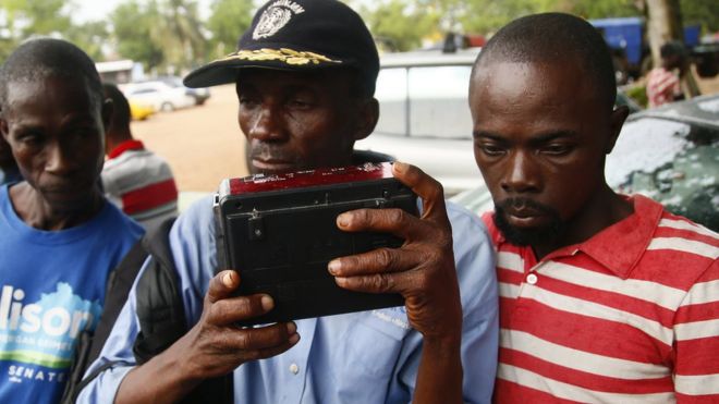 Supporters of Georgia Weah's Coalition for Democratic Change party listen for results from Liberia's presidential and general elections on the radio