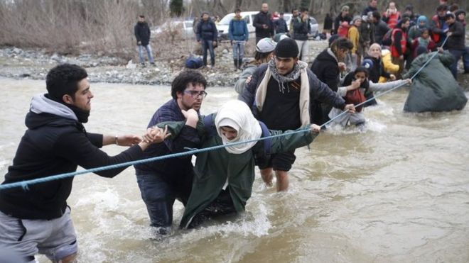 Migrants wade across a river near the Greek-Macedonian border. Photo: 14 March 2016