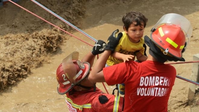 Voluntarios y bomberos rescatando a un niño en Perú.