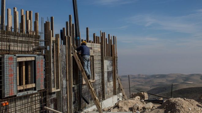 A Palestinian worker builds a new house in an Israeli settlement on 16 January 2017 in the West Bank