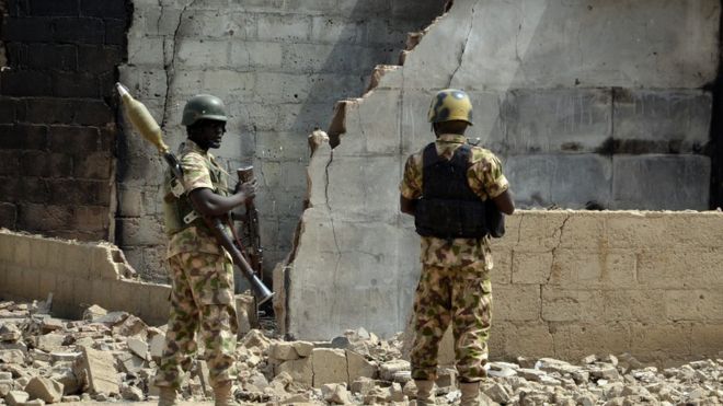 Soldiers looks at burnt house on 4 February 2016 during a visit to the village of Dalori village, some 12km from Borno state capital Maiduguri