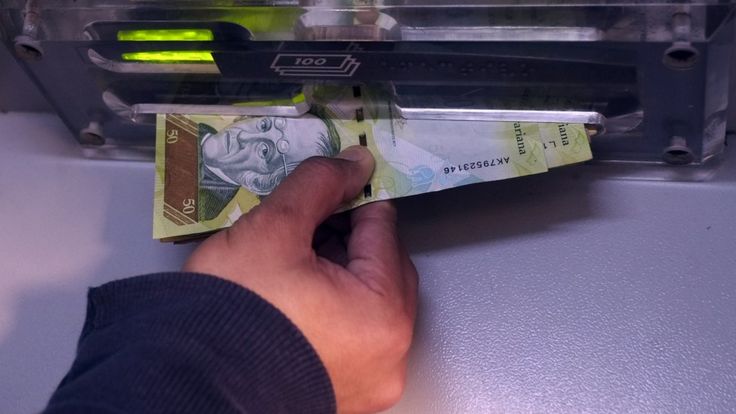 Una mano agarra los billetes del cajero automático