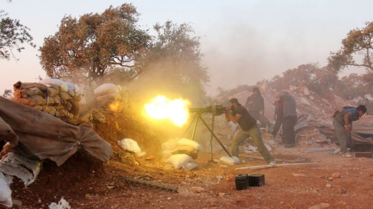 A rebel fighter fires heavy artillery during clashes with government forces in Idlib province