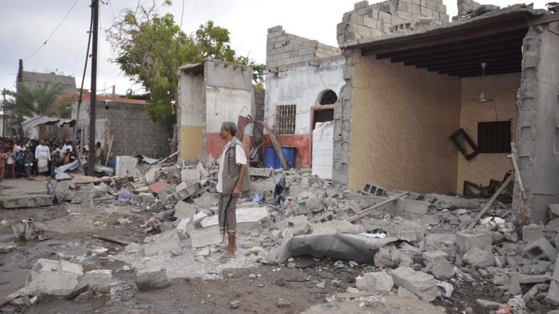 A man stands on the wreckage of a house destroyed by a Saudi-led air strike in Yemen's Red Sea port city of Houdieda