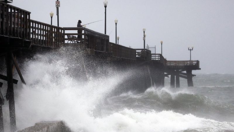 Waves crash against a pier in Seal Beach, California, on 17 February 2017