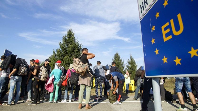 Migrants who arrived by bus from Croatia wait for Hungarian buses at the border crossing between Hungary and Croatia