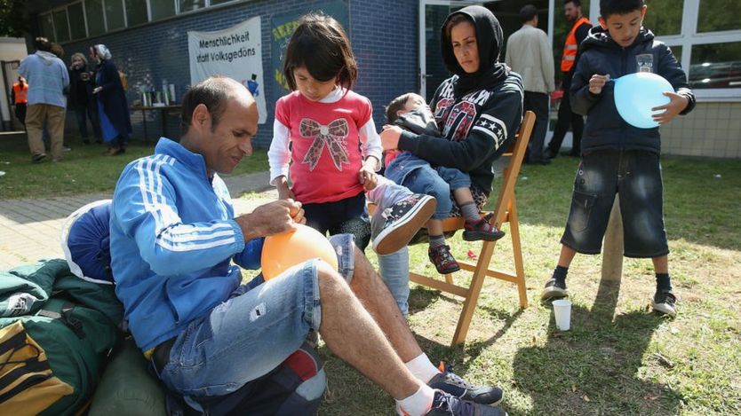 Family from Afghanistan sit outside the Jahn-Sporthalle gymnasium in Neukoelln district, Germany. 8 Sept 2015