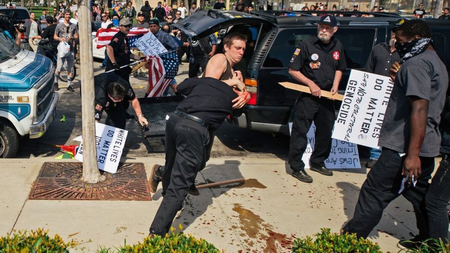 This photo provided by OC Weekly shows counter-protesters scuffling with a KKK member as he stabs an attacking protester, center, as members of the KKK try to start an anti-immigration rally at Pearson Park in Anaheim on Saturday, Feb. 27, 2016