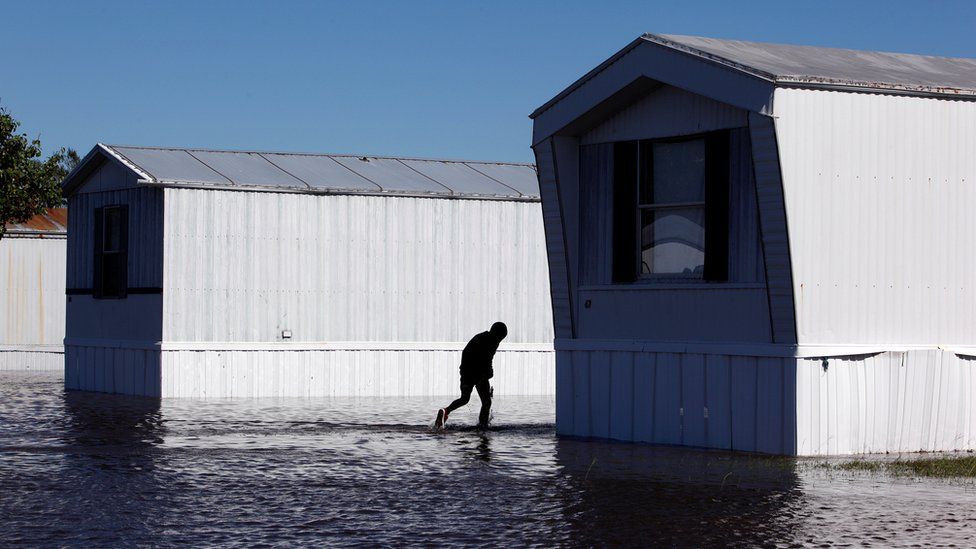 A young resident wades through flood waters at a trailer park after Hurricane Matthew hit Lumberton, North Carolina
