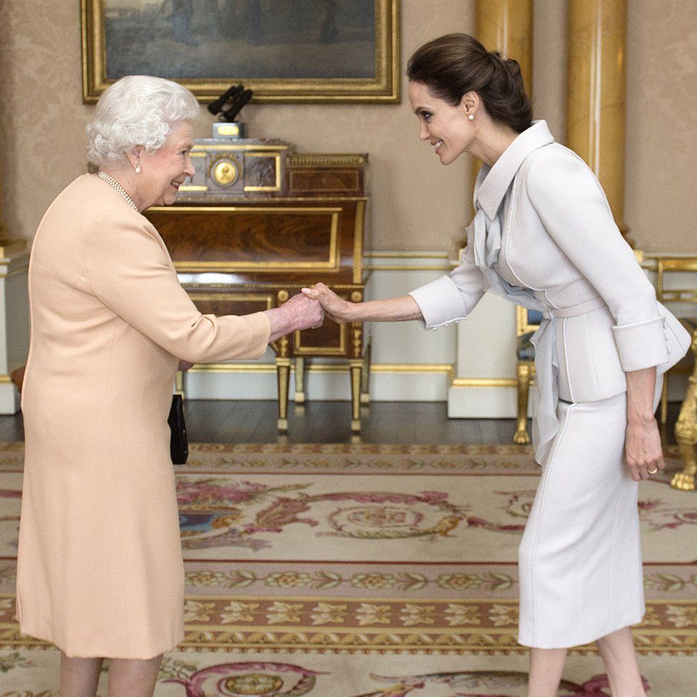 Actress Angelina Jolie being presented with the Insignia of an Honorary Dame Commander of the Most Distinguished Order of St Michael and St George by Queen Elizabeth II