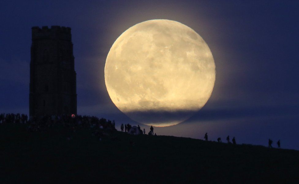 A full moon rises behind Glastonbury Tor