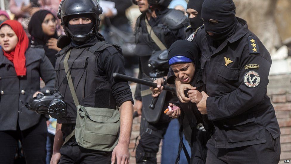 An Egyptian riot policeman detains a female student at al-Azhar University during a protest inside their campus in Cairo on 30 December 2013