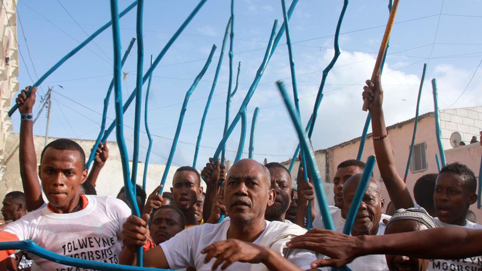 Somali people march through the streets with blue sticks during a traditional dance festival - Mogadishu, Somalia, Monday 18 July 2016