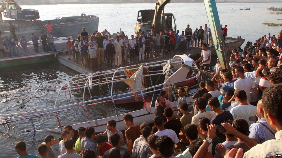 Relatives and onlookers gather on the bank of the Nile on 23 July 2015, as the wreckage of a boat is pulled out of the water