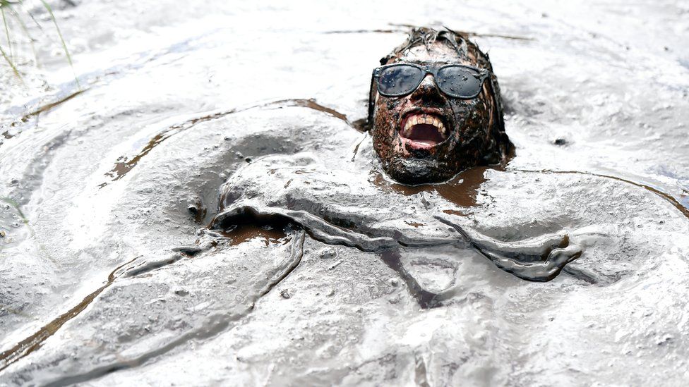 சேறு வழியாக போட்டியின் தூரத்தை கடக்கும் பங்கேற்பாளர்கள்